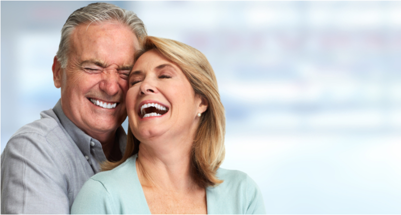 Happy elderly couple smiling with flexible partial dentures.