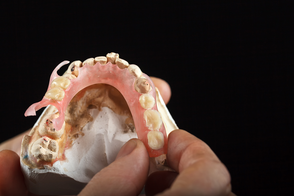 A dental technician carefully holding a denture, highlighting the craftsmanship involved in its creation