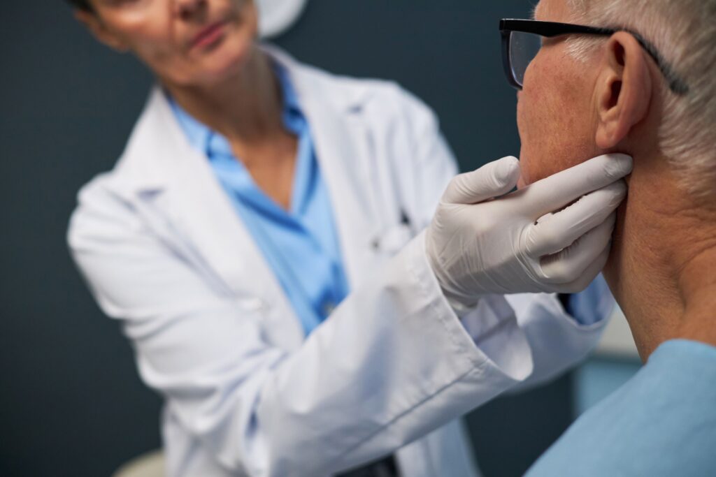 Medical professional examining elderly patient for cancer