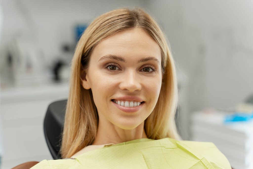 Woman in dental clinic smiling with dental crown and bridge