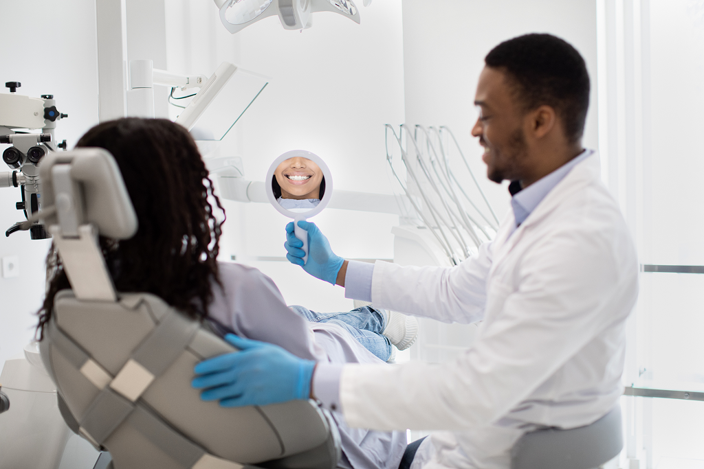 Woman at dental office in Winnipeg after tooth bonding looking at the mirror and smiling