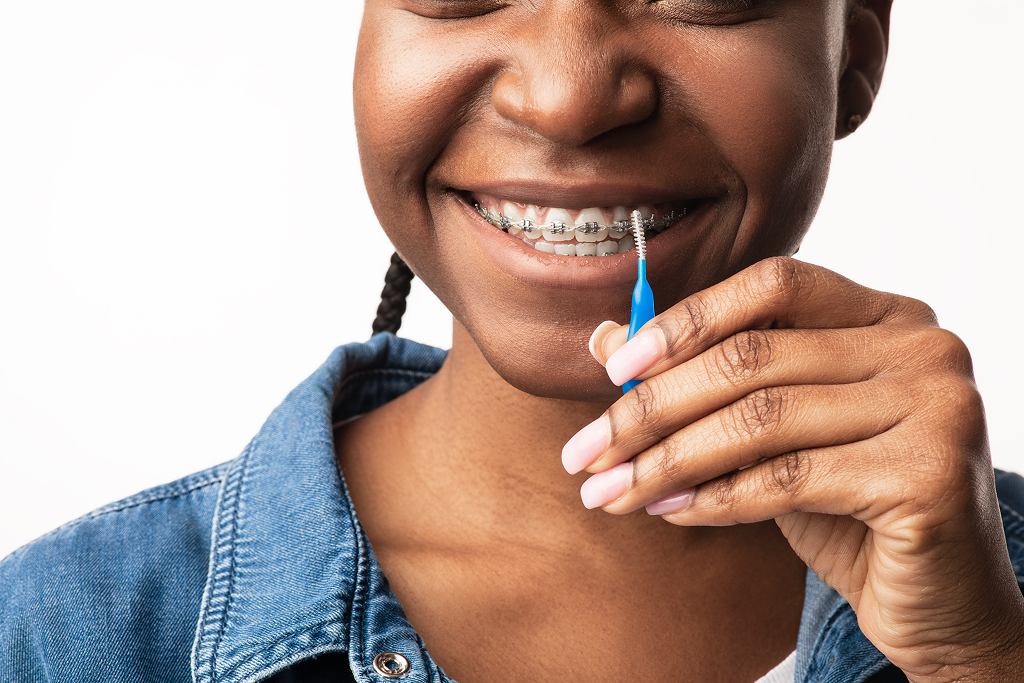 Woman cleaning her teeth with braces