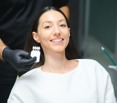 a lady on a dentist chair smiling with a veneer card