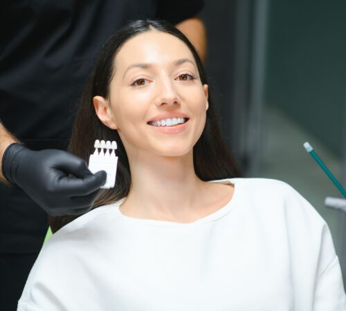 a lady on a dentist chair smiling with a veneer card