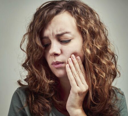 woman in pain holding her cheeks in dental emergency